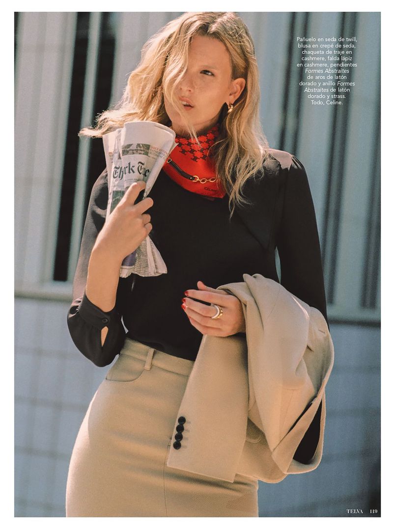 Model Mariina Keskitalo wearing a black top, beige skirt, and red neck scarf while holding a folded newspaper in an editorial shoot.