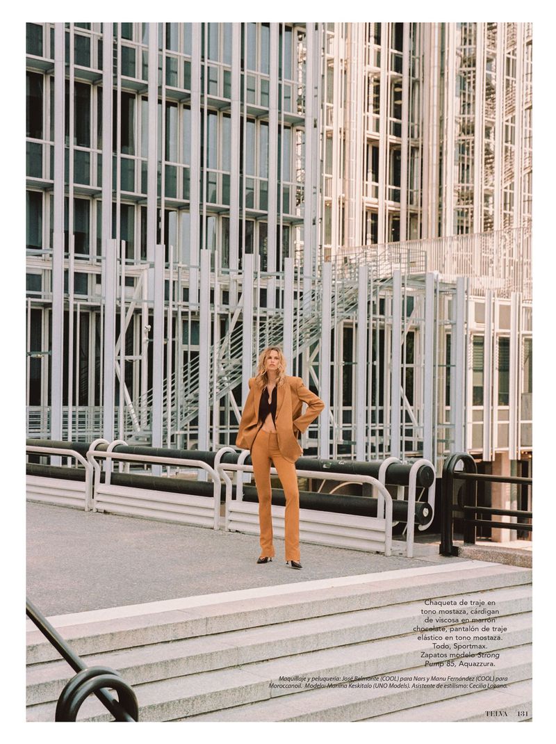 Woman in a brown suit poses in front of a modern office building. Editorial fashion shot with natural lighting. Fashion and architecture.