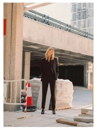 Model Mariina Keskitalo standing in a black tailored suit next to construction materials and a traffic cone.