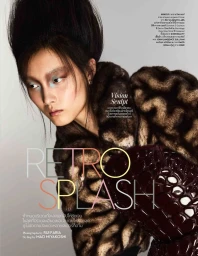 Model with voluminous updo hairstyle and textured patterned jacket holding a dark glossy bag against a grey background