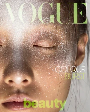 Close-up beauty portrait of an East Asian woman with closed eyes and fine white powder speckled across her face.