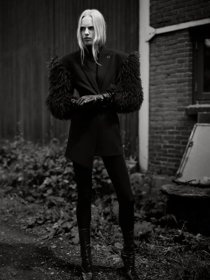 Model Marrit Krikke posing outdoors in a black tailored jacket with voluminous textured sleeves, gloves, and boots for Numéro France.