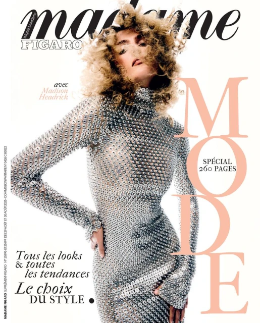 Fashion magazine cover featuring a woman with curly blonde hair wearing a silver, long-sleeved dress against a bright white background.