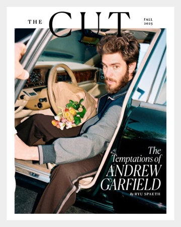 Andrew Garfield on The Cut magazine cover, Fall 2023 issue, seated in a car with flowers. The image has a soft, editorial style.