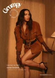 Jurnee Smollett wearing a brown suede jacket and striped gloves leaning against a wooden wall in Grumpy Magazine cover editorial