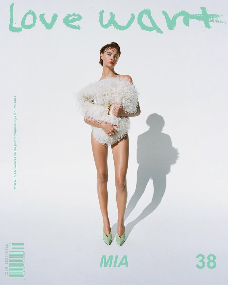 A young woman with short hair poses in front of a light background, wearing a fuzzy coat and light-colored heels for a fashion editorial.