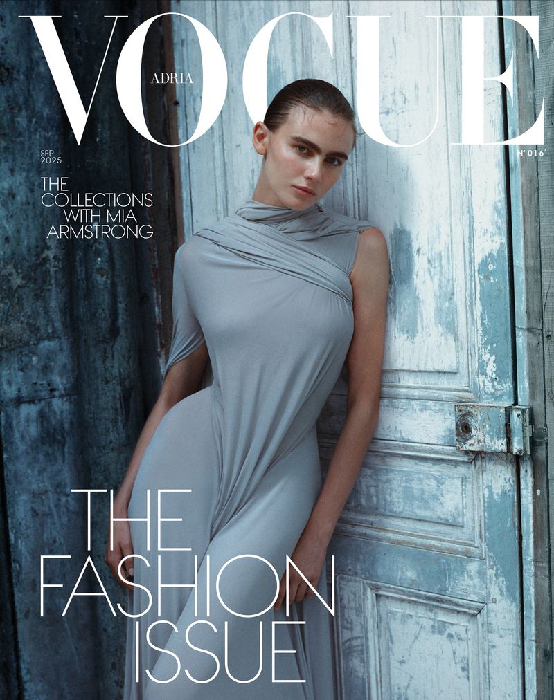 Vogue Adria cover featuring a woman in a gray dress leaning against a weathered blue door. The magazine title is prominently displayed.
