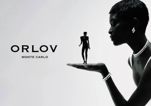 Black and white advertising image of a woman holding a miniature standing figure on her open palm while wearing diamond jewelry.