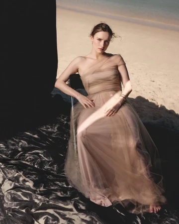 Woman sitting on a chair in a neutral tulle gown on a sandy beach for Sunday Life Australia editorial