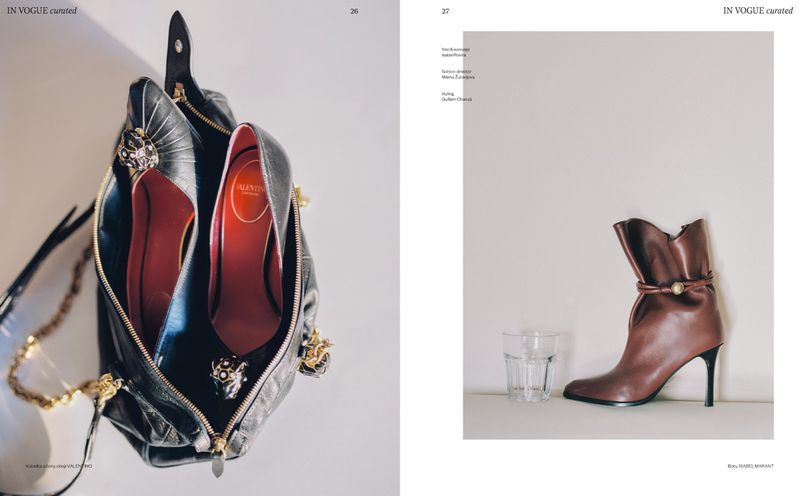 Fashion editorial shot featuring a black purse with jeweled high heels inside, displayed on a white background next to a brown boot.