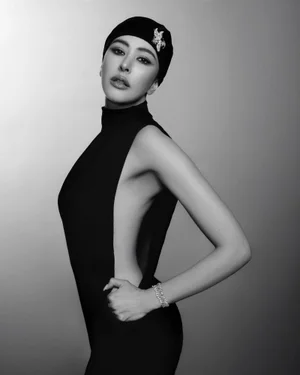 Sririta Jensen in a black sleeveless dress and matching cap posing for Harper's Bazaar Thailand in a monochrome studio portrait.