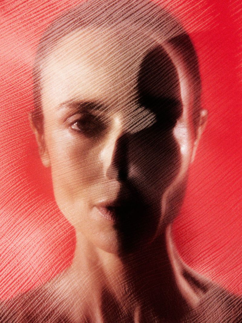 Close-up portrait of an adult female with geometric mesh overlay, featuring a red background and unique artistic visual effects.