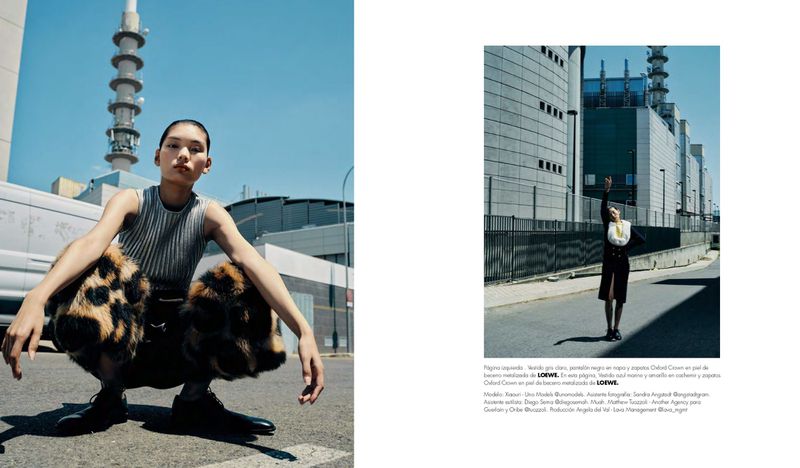 Fashion editorial shot of a model crouching in front of a brutalist building on a sunny day wearing a gray top and leopard-print pants.