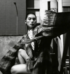 Model Xiaorui Li wearing an oversized textured plaid coat and white collared shirt posed outdoors in black and white.