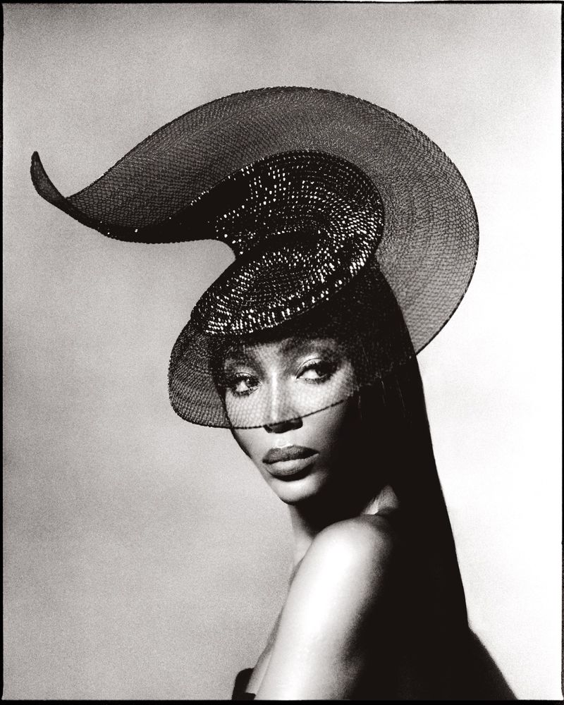 Elegant studio portrait of an adult female model wearing a black net hat, with her head turned to the side in a monochrome aesthetic.