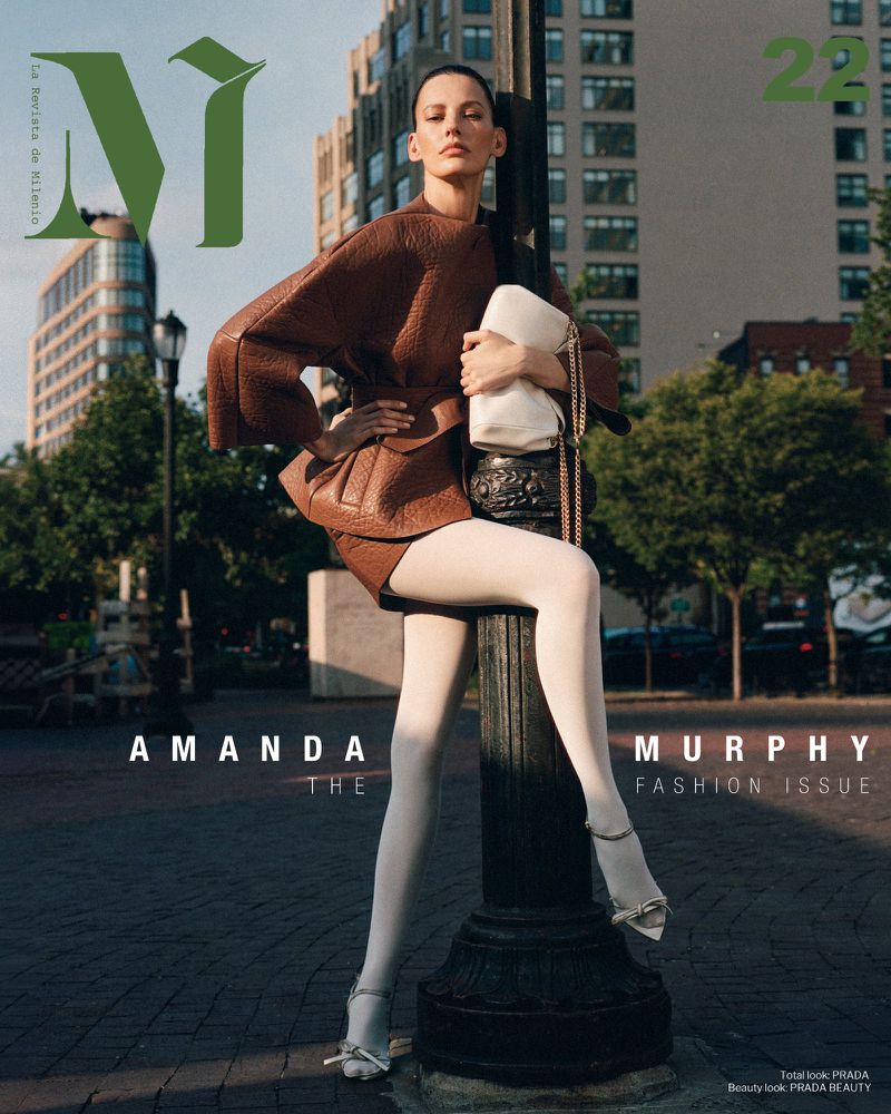 Magazine cover featuring a woman in a brown outfit, white tights, and heels, posing against a street lamp with buildings in the background.