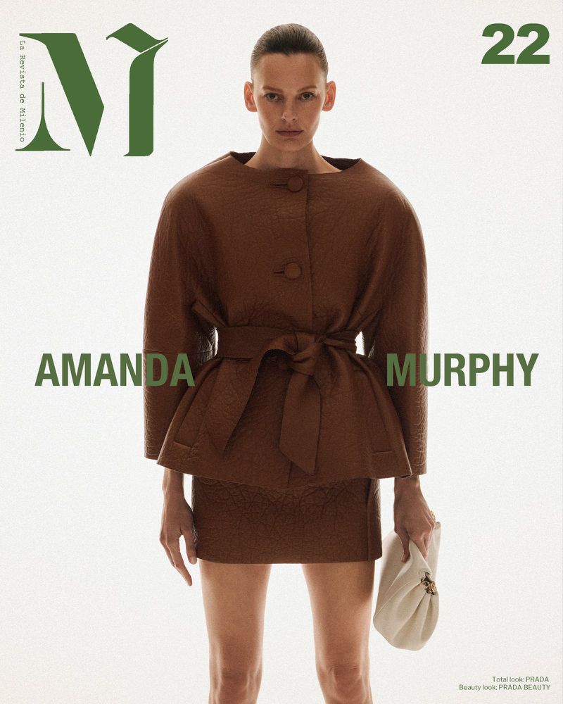 Magazine cover featuring an adult female fashion model wearing a brown jacket and skirt, holding a light-colored purse against a white background.