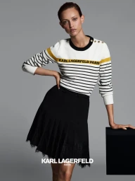Model wearing a striped sweater and black skirt posing against a plain grey studio backdrop for Karl Lagerfeld Paris