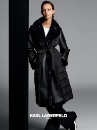 Model wearing a black quilted coat standing against a grey studio backdrop with a black pillar for Karl Lagerfeld.