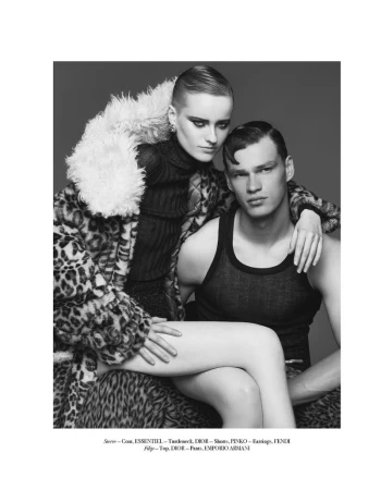Monochrome studio shot of a woman in leopard coat and man in tank top, seated with leg draped across him in fashion style.