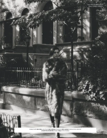 Woman in a fur coat walks on a sidewalk in front of a townhouse on a sunny day in a black and white lifestyle fashion shot.