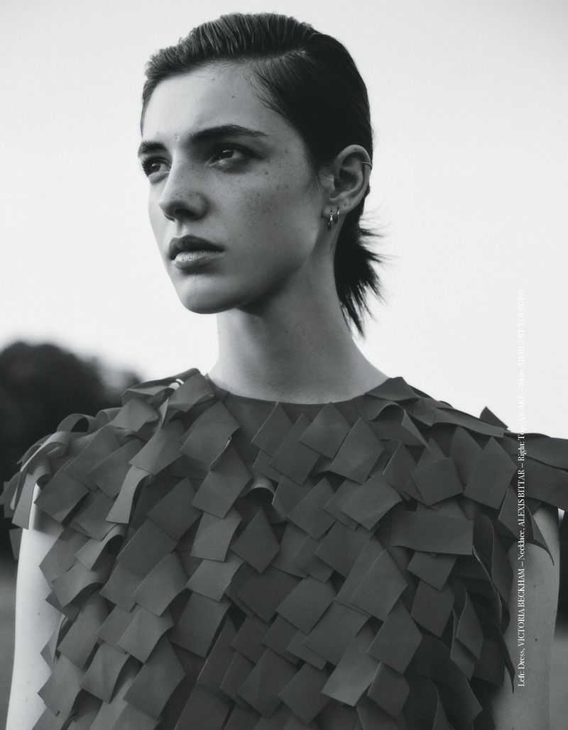 Monochrome portrait of a young woman with dark hair and eyes, wearing a patterned top, gazing into the distance against a bright sky backdrop.