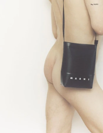 A naked individual is seen holding a black Marni handbag against a light, neutral background, presented in a portrait orientation.