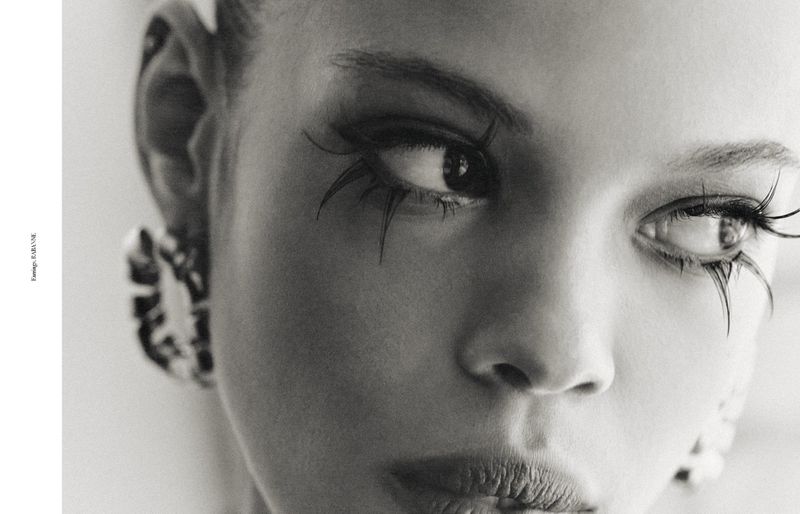Close-up black and white portrait of a woman with dramatic eyelashes and earrings, capturing an artistic beauty aesthetic.