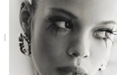 Monochrome close-up beauty portrait of model Amandine Pouilly wearing dramatic spiky false eyelashes and statement earrings.