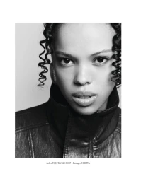 Close-up black and white portrait of a model wearing a high collar leather jacket against a plain background.
