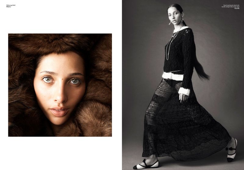 Black and white studio fashion shot of a woman in a long sheer black skirt and a textured black top with fur accents.