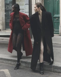 Two female models in long coats walking on a city street for a Vogue Ukraine editorial photographed by Emil Dietrich.