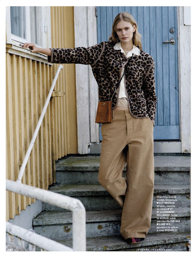 Blonde fashion model poses on outdoor steps wearing a leopard-print cardigan, wide-leg tan pants, and a small leather shoulder bag.