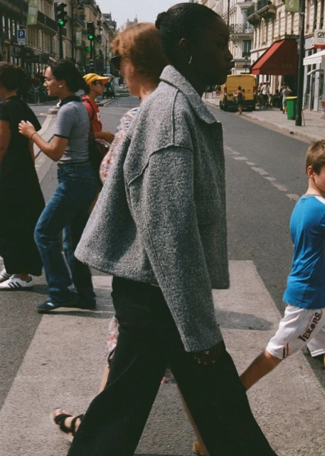 A group of people cross a city street at a crosswalk on a sunny day. Pedestrians walking in an urban environment with buildings and traffic.