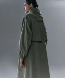 Model wearing an olive green hooded raincoat standing against a neutral studio background
