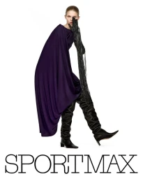 Model wearing a deep purple dress, black leather boots, and fringed gloves against a white backdrop for Sportmax