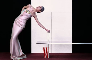 Model Qun Ye in an iridescent pink strapless gown leaning against a minimalist silver bench for W Magazine China.