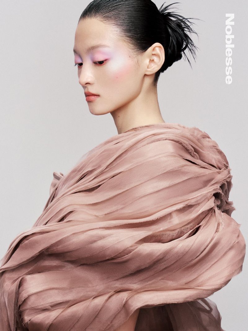 Asian woman portrait in dusty pink gown. Fashion shot with slicked back hair, pastel makeup, and a high-fashion gown against a grey background.