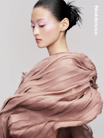 Asian woman portrait in dusty pink gown. Fashion shot with slicked back hair, pastel makeup, and a high-fashion gown against a grey background.