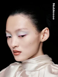 Close-up portrait of an East Asian model with pastel eyeshadow and white collar against a dark background for Noblesse Korea.