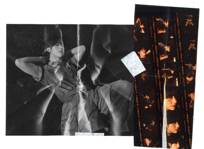 A black and white photo of an adult laying on grass, constructed of paper and tape alongside film strip with images.
