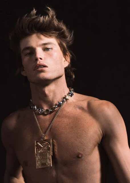 Model Jordan Barrett wearing a large pendant necklace against a black background