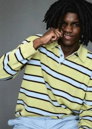 Black man with dreadlocks wearing a striped polo shirt against a grey background for HERO Summer Zine Fits