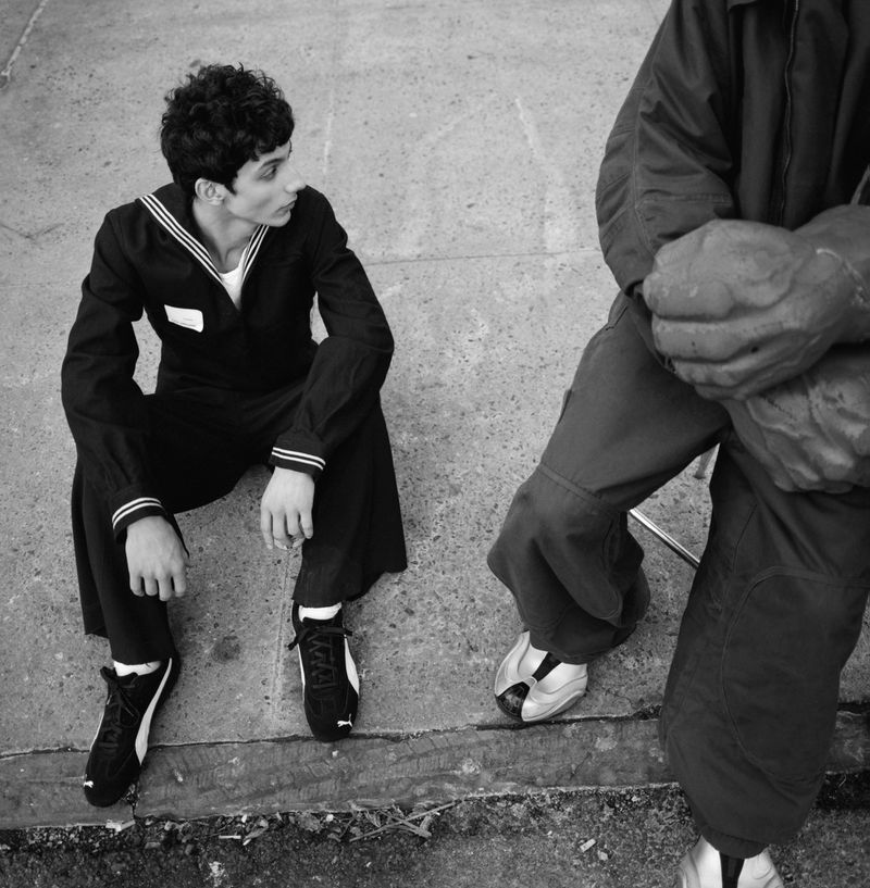 Black and white shot of two men outdoors, one in a sailor suit, the other in a jacket, providing a candid and realistic street scene.