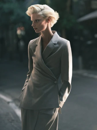 Mila van Eeten posing in a grey tailored wrap blazer on an urban street for Mytheresa FW25.