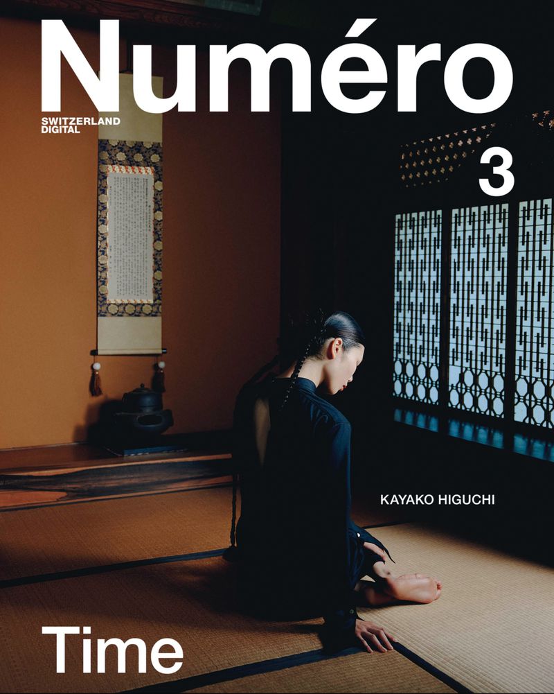 Numero magazine cover featuring a woman sitting on a mat in a room with dark walls and Japanese design details; moody studio shot.