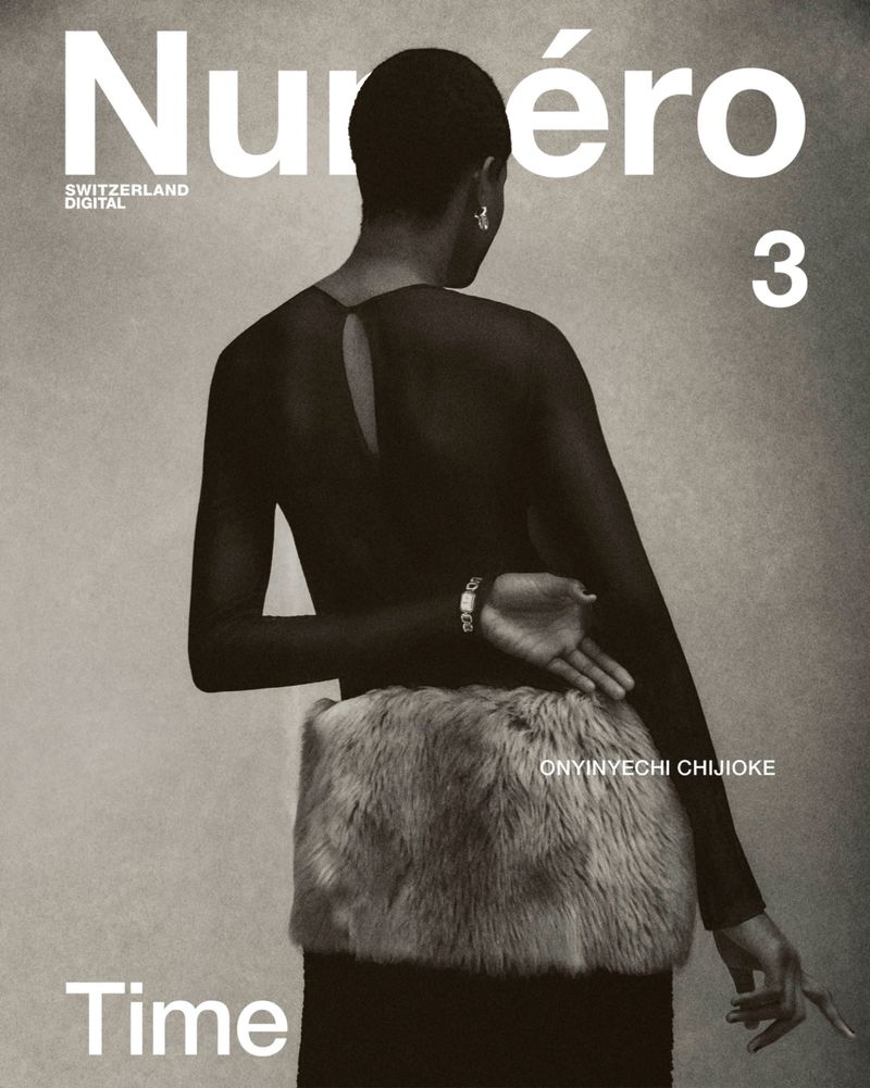 Magazine cover featuring an adult female with short hair wearing a black top and a furry object around her waist against a grey backdrop.