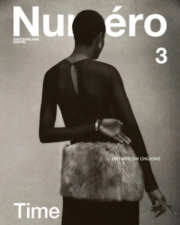 Magazine cover featuring an adult female with short hair wearing a black top and a furry object around her waist against a grey backdrop.