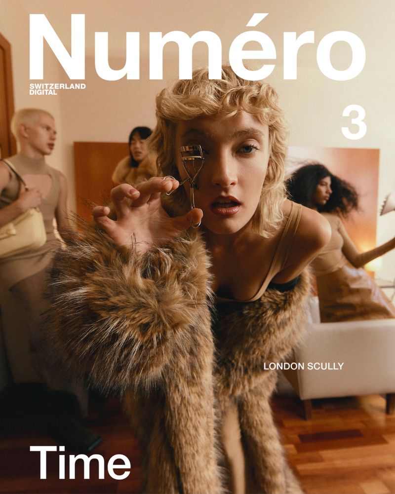 Magazine cover featuring a young adult female model with blond curly hair wearing fur coat holding eyelash curler with other models blurred.