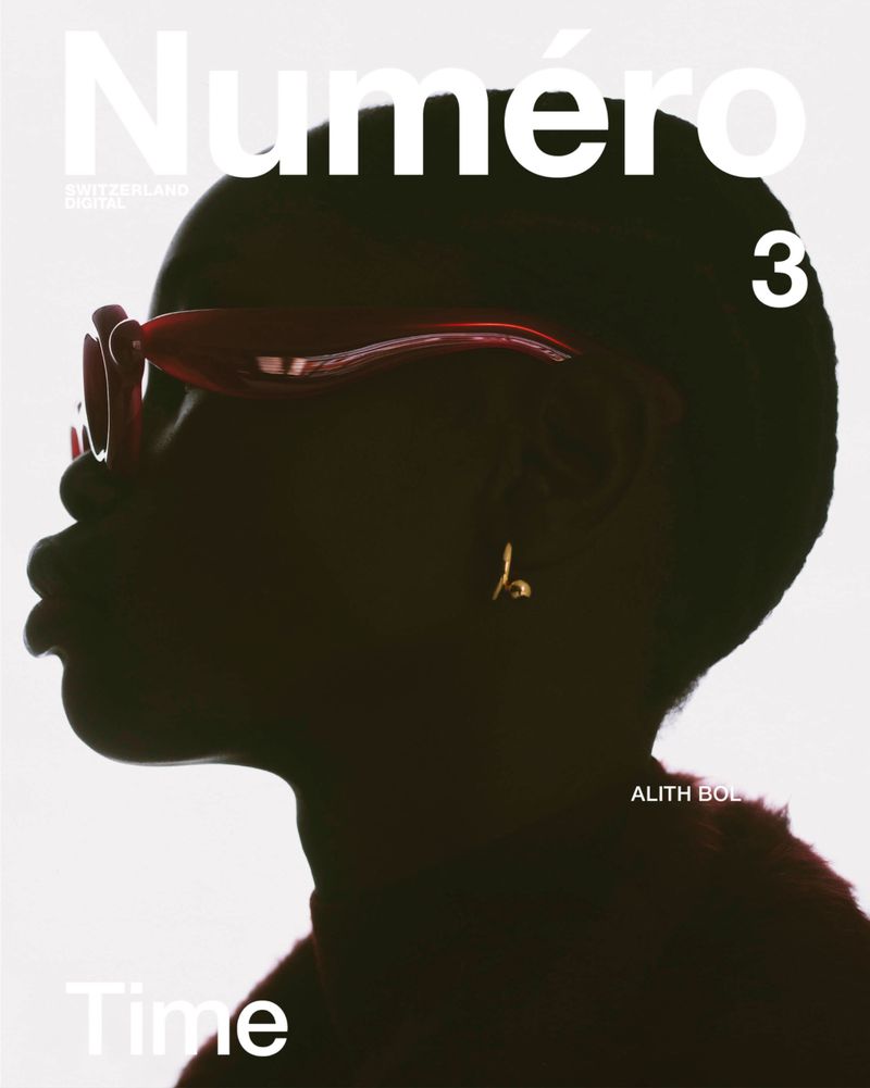 Profile silhouette portrait of model Alith Bol wearing red sunglasses and a small gold earring against a bright white background.